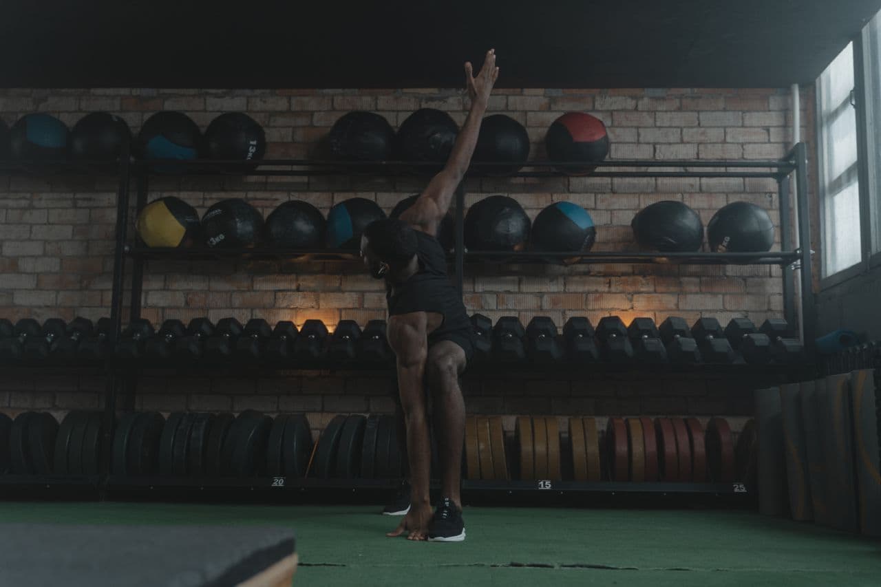 Un homme effectue un exercice d’étirement dans une salle de sport.